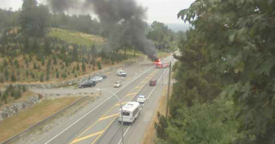 Traffic camera shows emergency crew arriving to a roadside fire in British Columbia